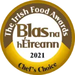 A gold and white circular badge with text: "The Irish Food Awards, Blas na hÉireann 2021, Chef’s Choice.