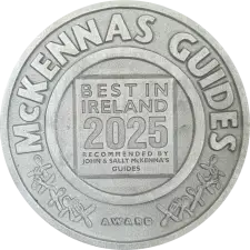 A silver medallion featuring the words "McKenna's Guides" around the edge, and "Best in Ireland 2025 Recommended by John & Sally McKenna's Guides Award" in the center.